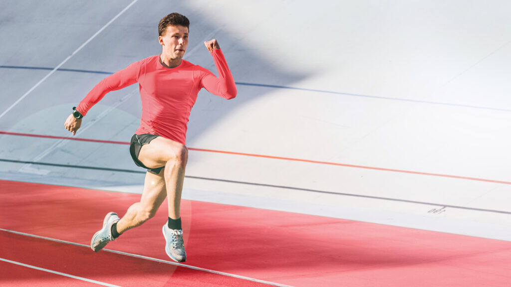 Foto von einem in rot gekleideten Sportler der gerade auf einer Rennstrecke sprintet