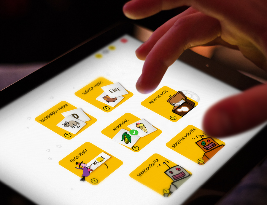 Ein Foto von einem Tabletbildschirm, auf dem verschiedene Spiele angezeigt werden. Eine Kinderhand tippt auf den Bildschirm.
