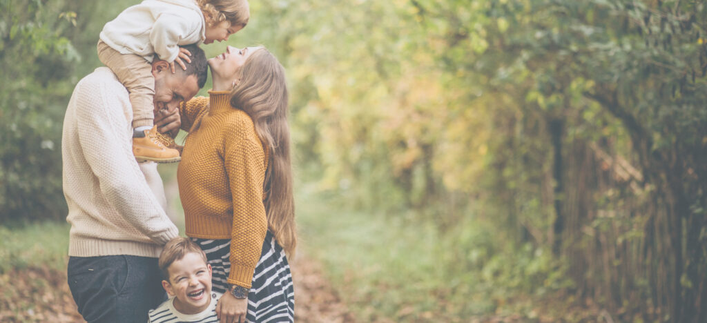 Foto einer jungen, glücklichen Familie mit zwei Kindern im Wald