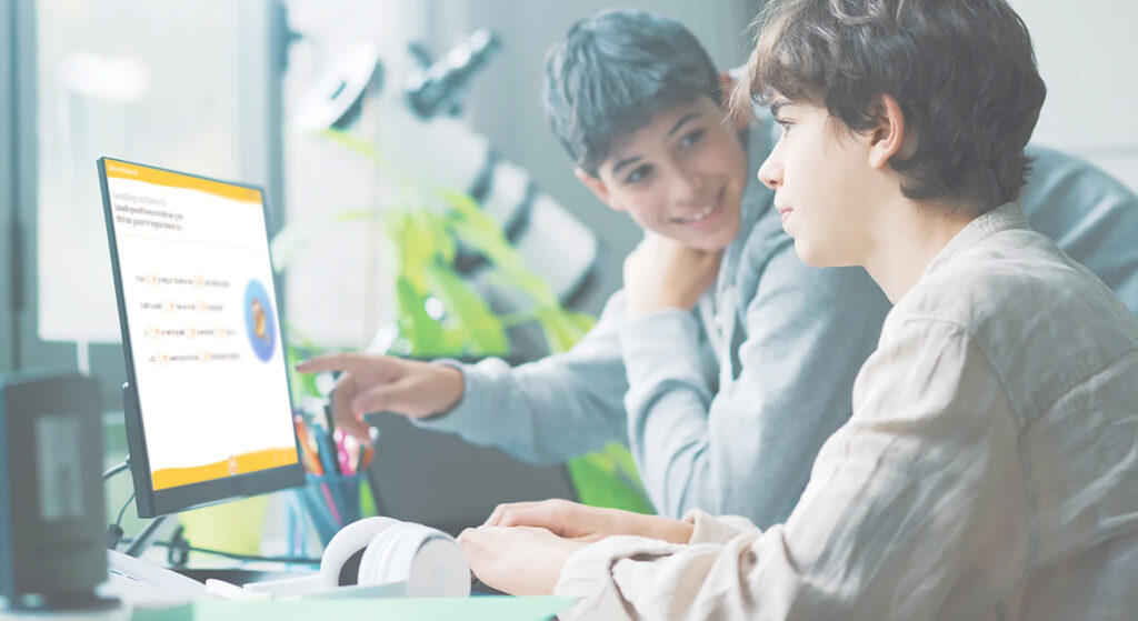 Zwei Jungen sitzen vor einem Computer auf dem ein Lernspiel angezeigt wird.