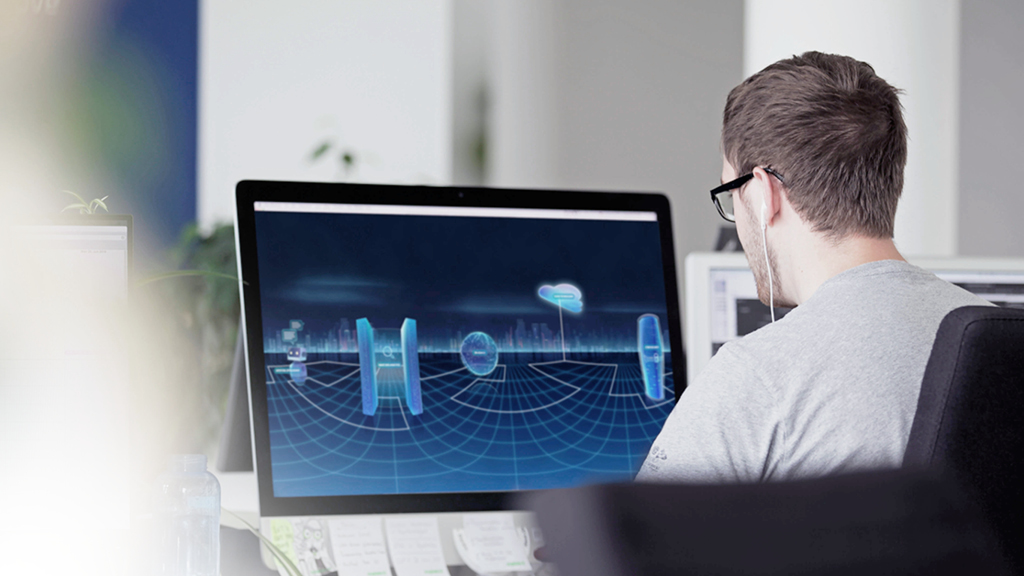 Foto eines Designers der vor einem Computerbildschirm sitzt und gerade an etwas arbeitet.
