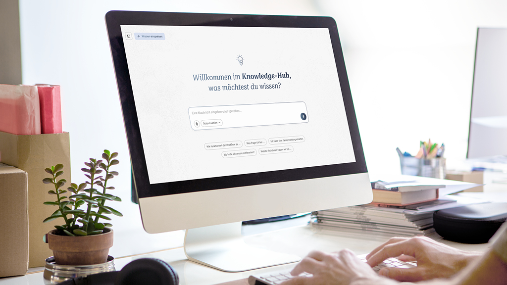 Computerbildschirm mit Knowledge-Hub-Startseite, Eingabezeile, Person tippt, Nahaufnahme auf Pflanzen und