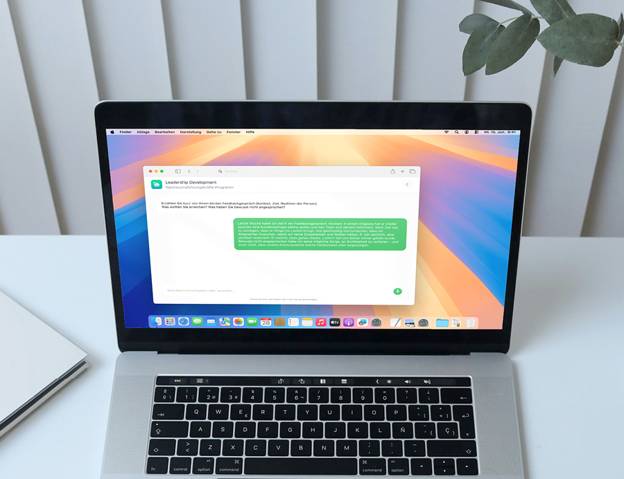 Laptop auf Schreibtisch zeigt Leadership Development Programm auf dem Bildschirm, umgeben von Pflanzen.