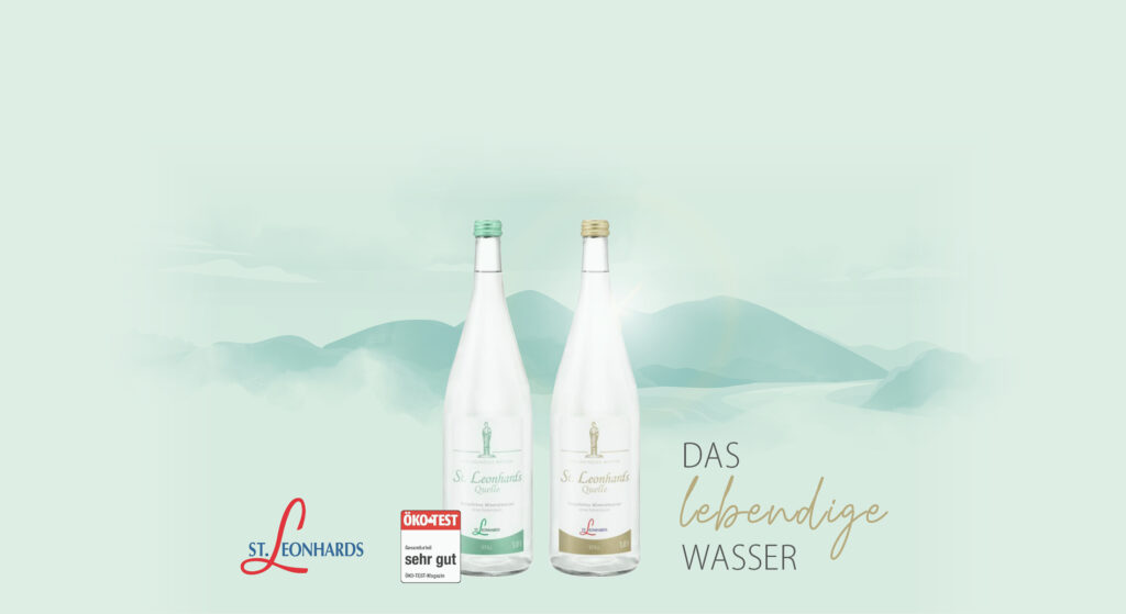 Zwei Flaschen St. Leonhardsquelle Wasser vor einer Berglandschaft mit dem Text