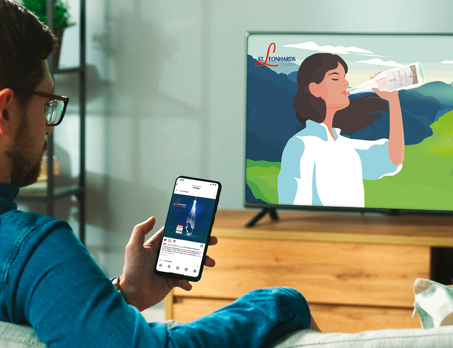 Ein Mann schaut auf ein Smartphone und einen Fernseher, die beide Werbung für St. Leonhardsquelle zeigen.